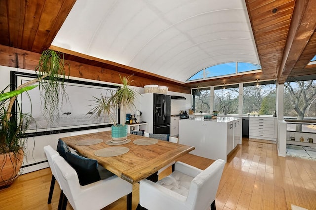 dining space with vaulted ceiling, a baseboard radiator, and light hardwood / wood-style flooring