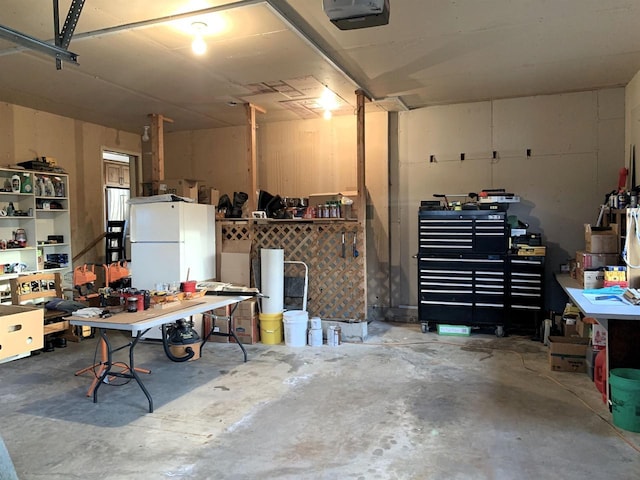 garage featuring white refrigerator, a garage door opener, and a workshop area