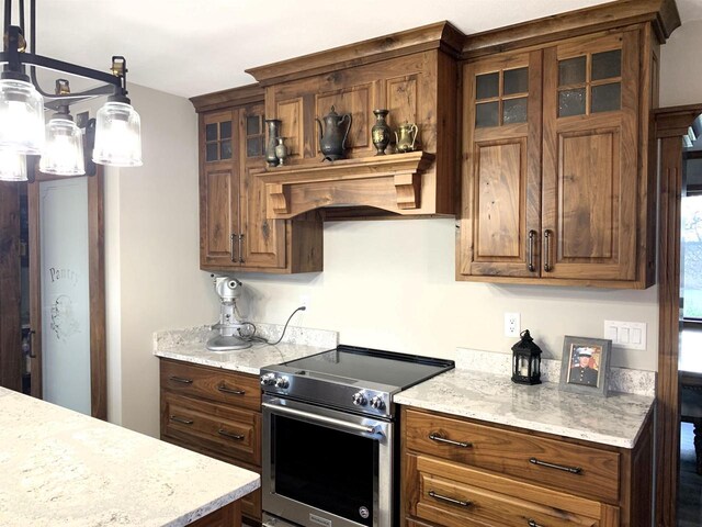 kitchen featuring hanging light fixtures, electric range, and light stone counters