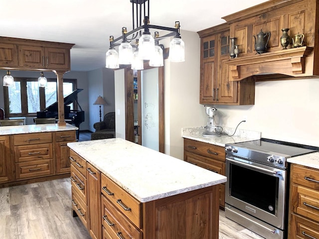 kitchen featuring hardwood / wood-style floors, hanging light fixtures, a center island, high end stainless steel range, and light stone counters