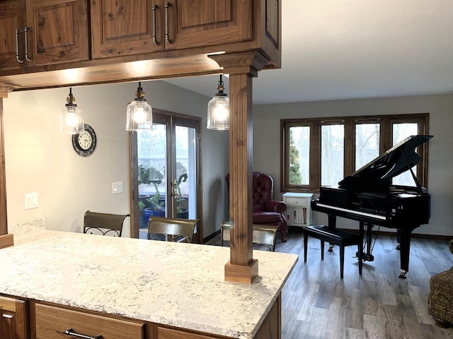 kitchen featuring hanging light fixtures, light stone countertops, dark hardwood / wood-style floors, and ornate columns