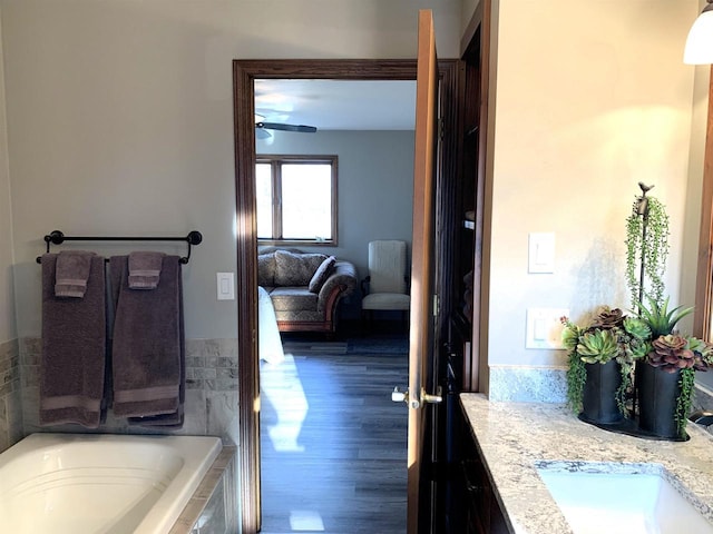 bathroom featuring hardwood / wood-style floors, vanity, and a relaxing tiled tub