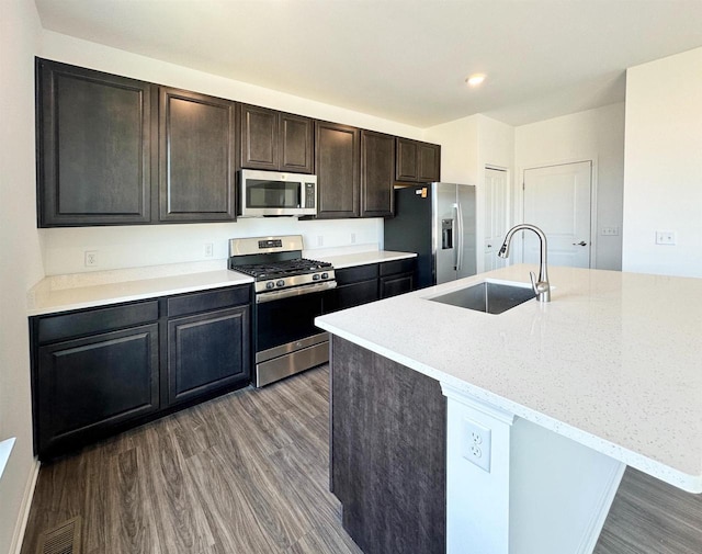 kitchen featuring a kitchen island with sink, appliances with stainless steel finishes, a sink, and wood finished floors