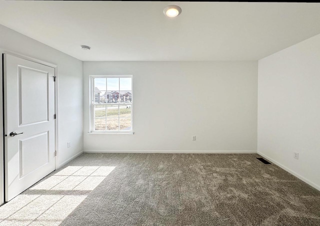 carpeted spare room featuring visible vents and baseboards