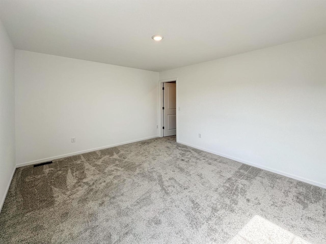 unfurnished room featuring carpet floors, visible vents, and baseboards