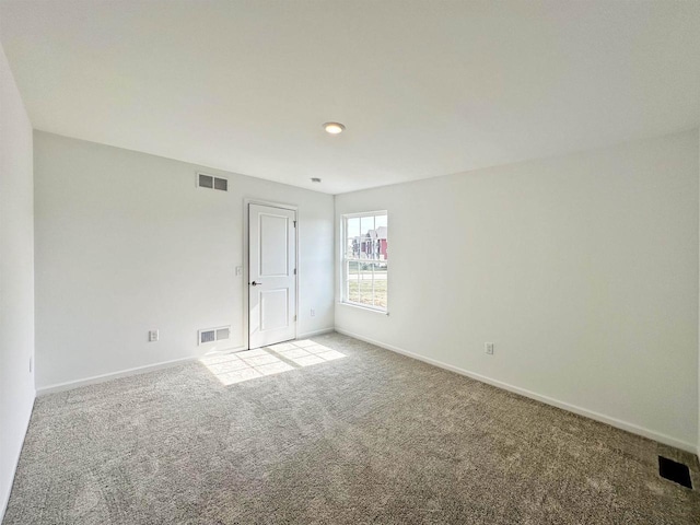 carpeted spare room with visible vents and baseboards