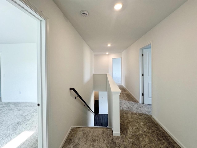 hall with carpet floors, baseboards, and an upstairs landing