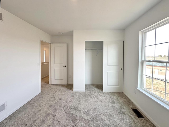 unfurnished bedroom with carpet, baseboards, visible vents, and a closet