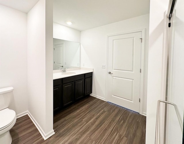 bathroom with toilet, baseboards, wood finished floors, and vanity