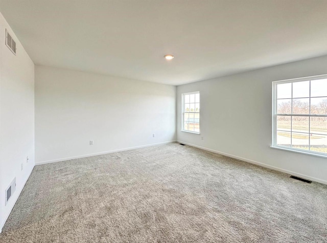 empty room with carpet floors, baseboards, and visible vents