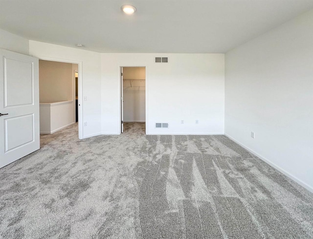 unfurnished bedroom featuring baseboards, visible vents, a spacious closet, and carpet flooring