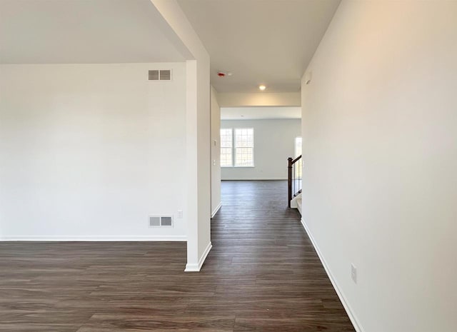 hall featuring dark wood-type flooring, visible vents, stairway, and baseboards