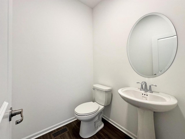 half bath featuring visible vents, toilet, baseboards, and wood finished floors