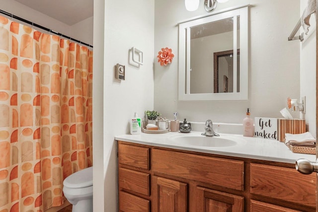 bathroom with walk in shower, vanity, and toilet