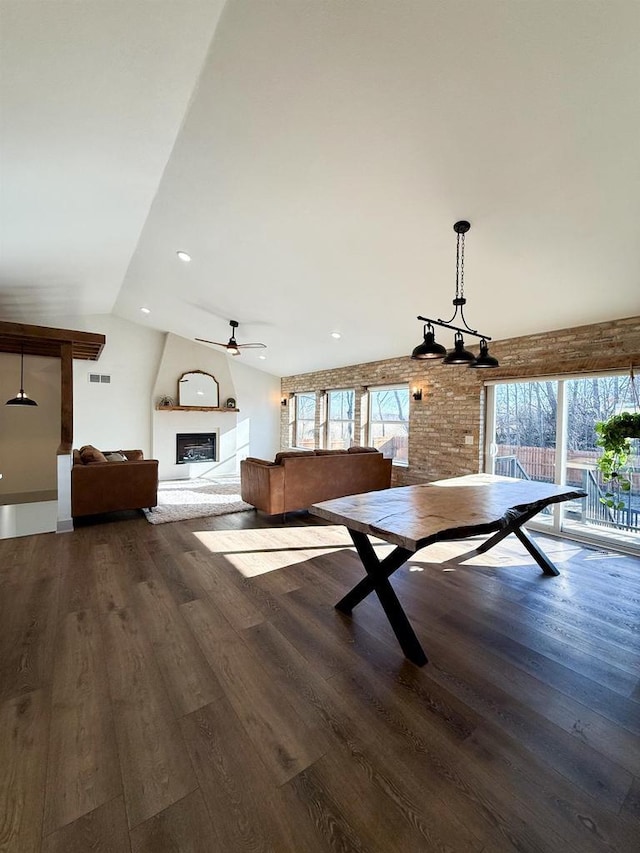 unfurnished dining area featuring hardwood / wood-style flooring, lofted ceiling, a large fireplace, and ceiling fan