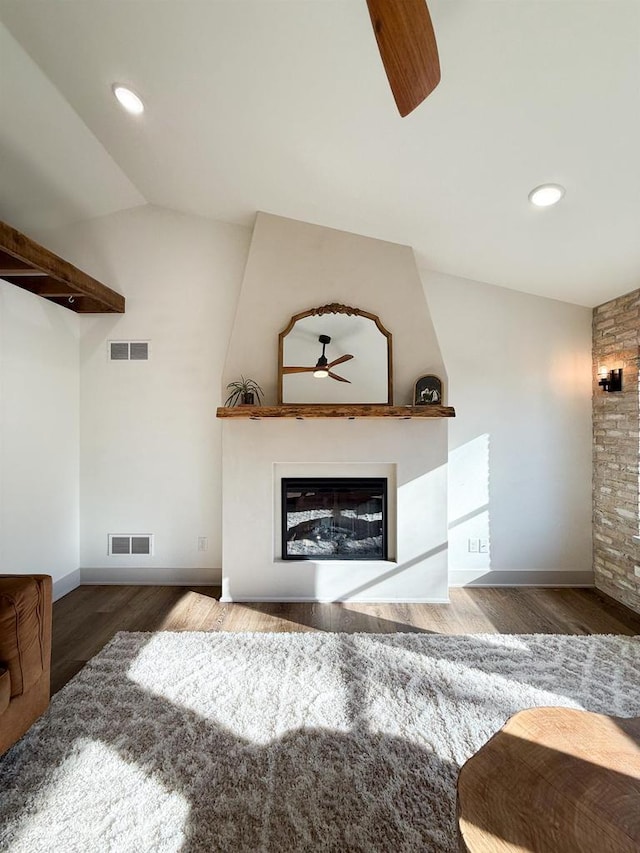 living room featuring lofted ceiling, a fireplace, dark hardwood / wood-style floors, and ceiling fan