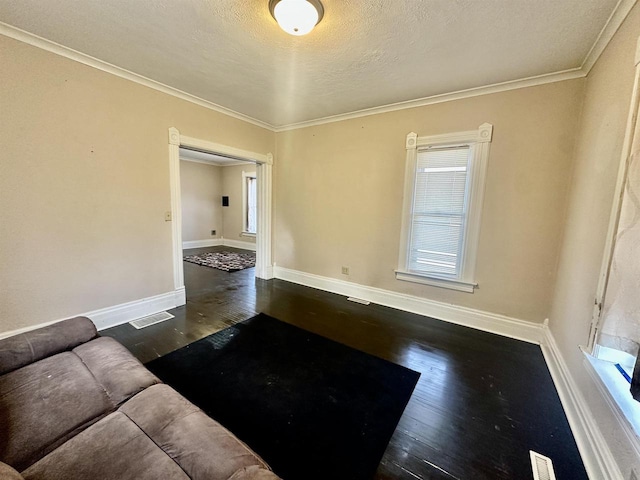 unfurnished living room featuring dark wood-type flooring, ornamental molding, and a textured ceiling