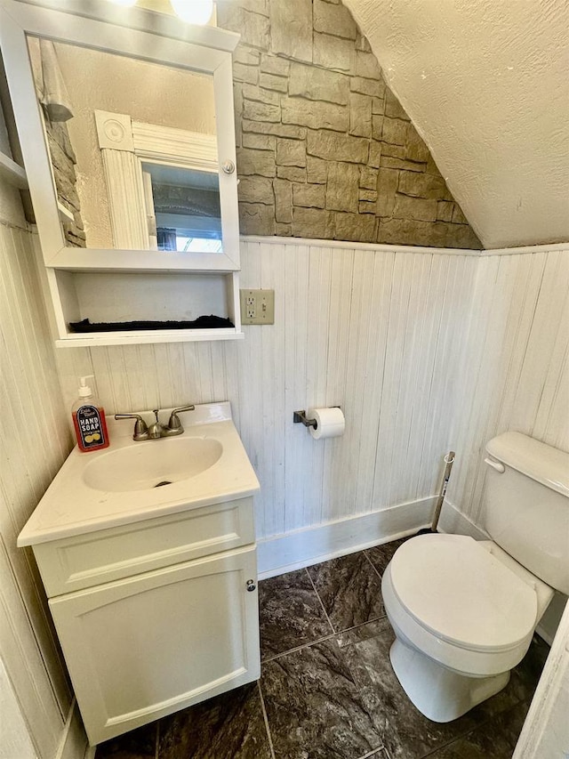 bathroom featuring vanity, toilet, and wood walls