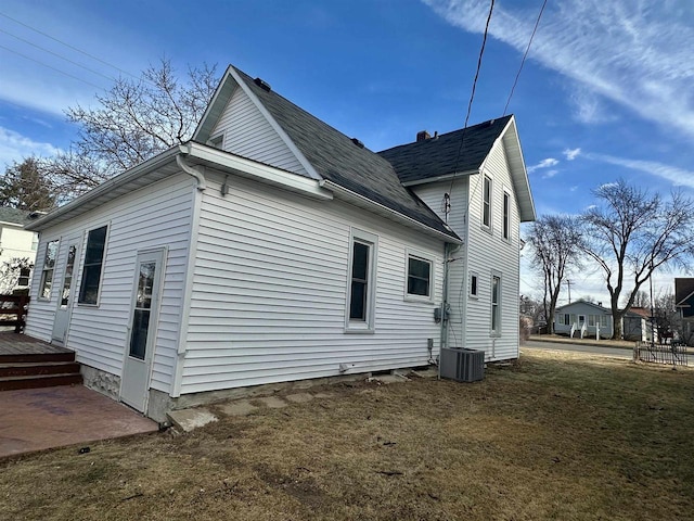 view of side of property featuring central AC unit and a yard