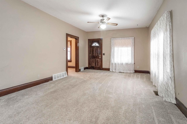 unfurnished living room with light colored carpet and ceiling fan