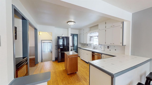 kitchen featuring dishwasher, black refrigerator, a center island, white cabinets, and kitchen peninsula