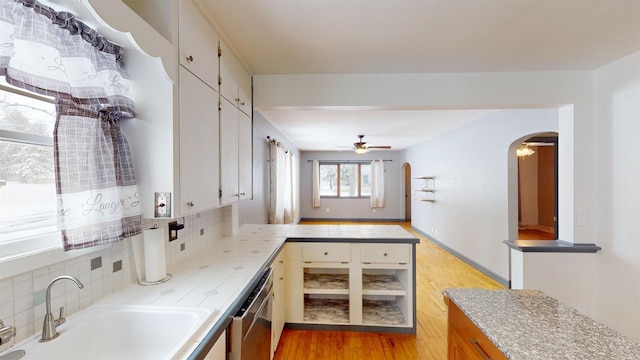 kitchen with dishwasher, sink, backsplash, ceiling fan, and light hardwood / wood-style floors