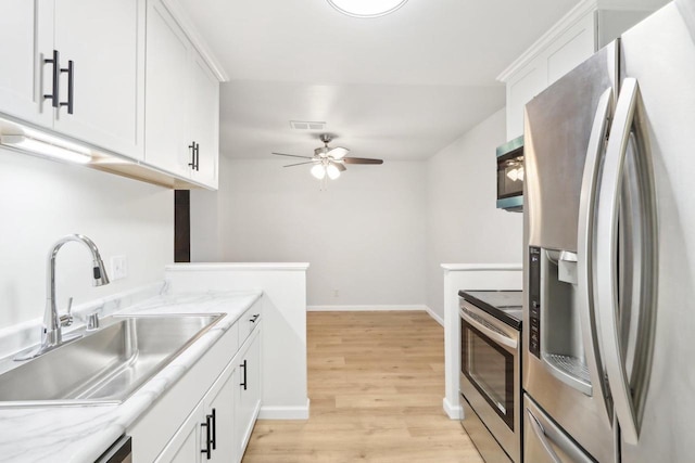 kitchen with sink, white cabinetry, stainless steel appliances, light stone countertops, and light wood-type flooring