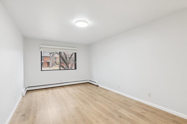 empty room featuring a baseboard radiator and light hardwood / wood-style flooring