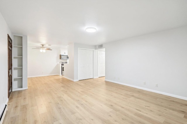 spare room featuring ceiling fan, built in shelves, baseboard heating, and light wood-type flooring