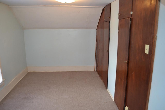 bonus room with vaulted ceiling and light colored carpet