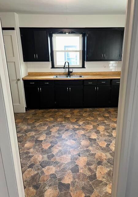 kitchen featuring butcher block counters, sink, and backsplash