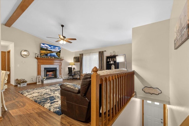 living room featuring hardwood / wood-style flooring, ceiling fan, a fireplace, and lofted ceiling with beams