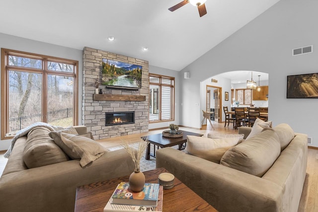 living room with a stone fireplace, plenty of natural light, and light wood-type flooring