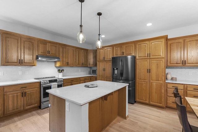 kitchen with light wood-type flooring, light stone countertops, a center island, and appliances with stainless steel finishes