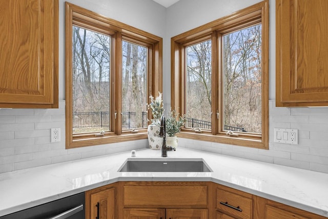 details with tasteful backsplash, sink, light stone countertops, and black dishwasher