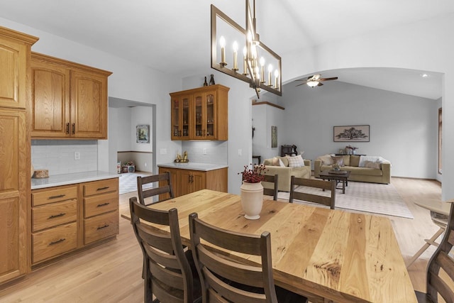 dining room featuring lofted ceiling, ceiling fan with notable chandelier, and light wood-type flooring