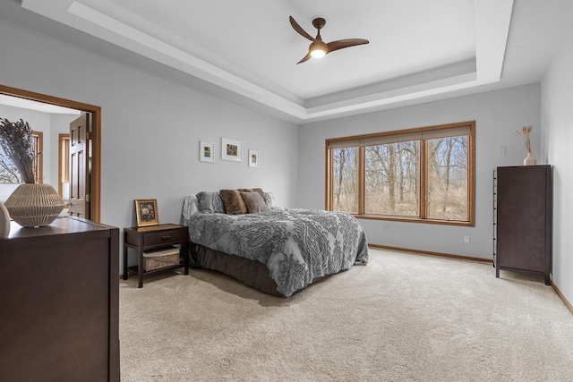 bedroom with ceiling fan, a raised ceiling, and light carpet