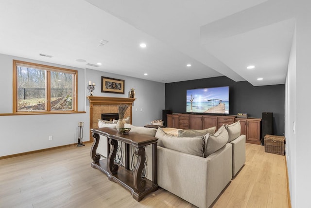 home theater featuring light hardwood / wood-style floors and a tile fireplace