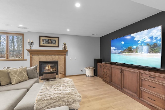 living room with a tiled fireplace and light hardwood / wood-style flooring