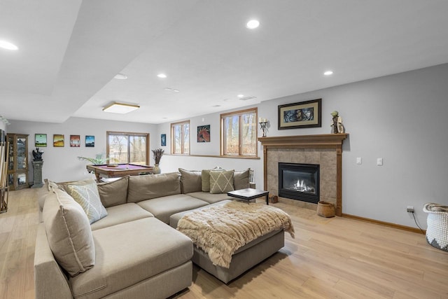 living room with billiards, a tiled fireplace, and light hardwood / wood-style flooring