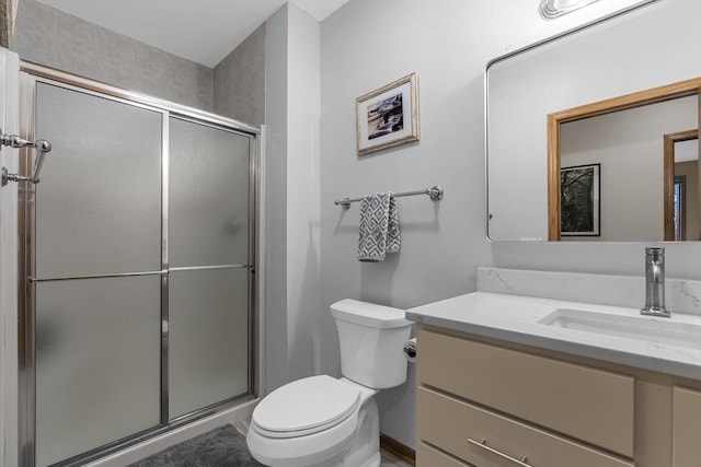 bathroom featuring vanity, a shower with shower door, and toilet