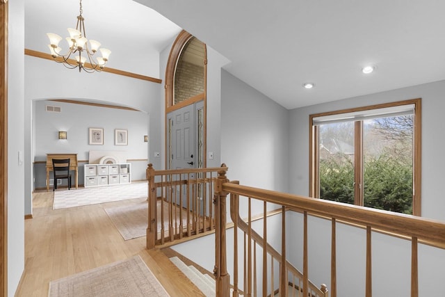 hallway featuring lofted ceiling, a notable chandelier, and light hardwood / wood-style floors