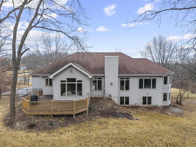 rear view of house featuring a wooden deck and a lawn