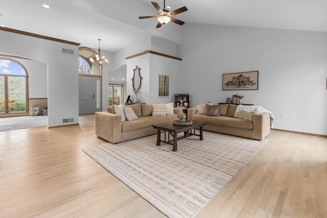 living room with ceiling fan with notable chandelier, high vaulted ceiling, and light hardwood / wood-style floors