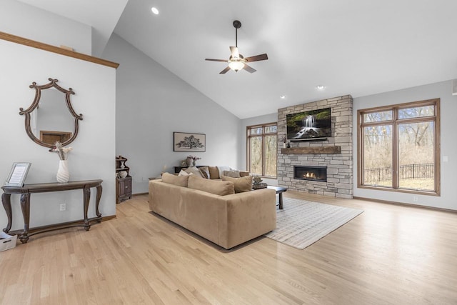 living room featuring ceiling fan, high vaulted ceiling, a fireplace, and light hardwood / wood-style floors