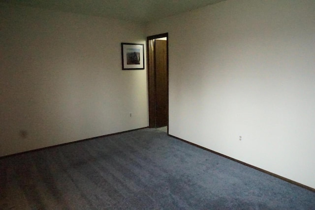 unfurnished room featuring dark colored carpet