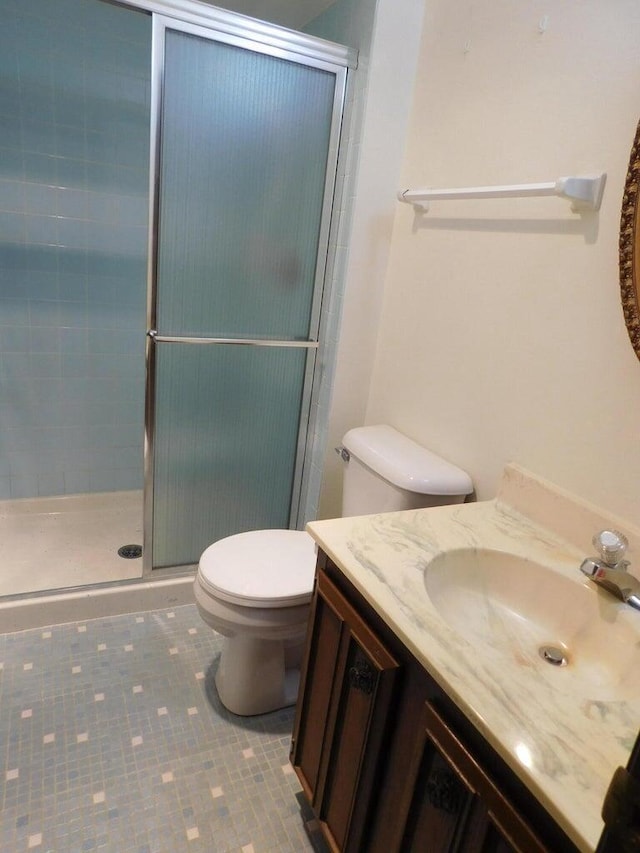 bathroom with vanity, toilet, a shower with shower door, and tile patterned flooring