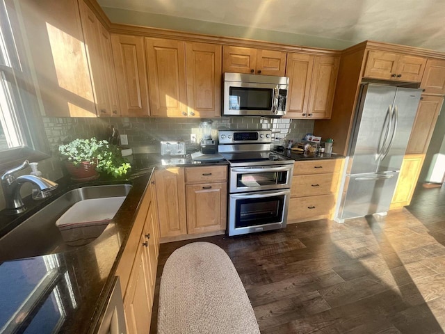 kitchen with appliances with stainless steel finishes, sink, dark wood-type flooring, and decorative backsplash