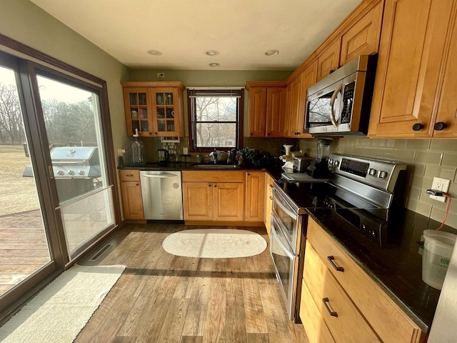 kitchen with stainless steel appliances, light hardwood / wood-style floors, sink, and decorative backsplash