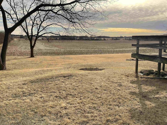 yard at dusk featuring a rural view